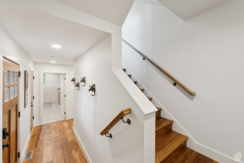 Stairs with wood finished floors and recessed lighting