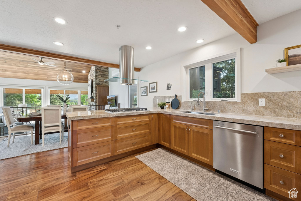 Kitchen featuring stainless steel appliances, light wood finished floors, a peninsula, brown cabinets, and beamed ceiling