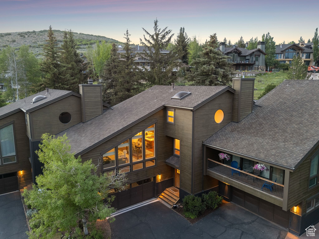 View of front of home featuring a chimney, roof with shingles, an attached garage, driveway, and a residential view