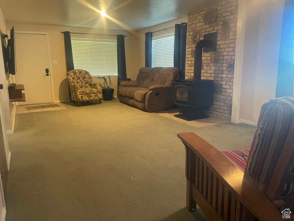 Carpeted living room featuring a wood stove and baseboards