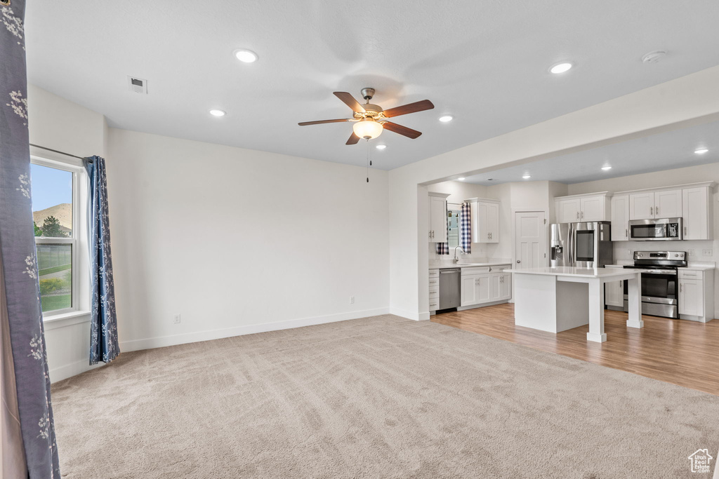 Unfurnished living room featuring light colored carpet, a ceiling fan, and recessed lighting