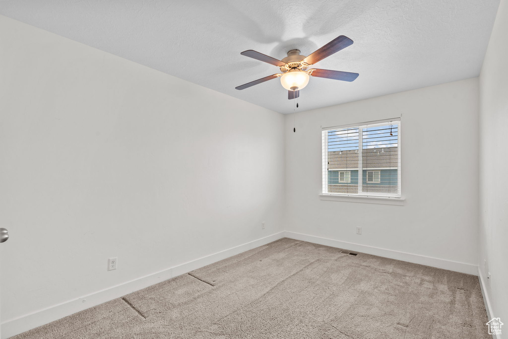Carpeted spare room with a ceiling fan and baseboards