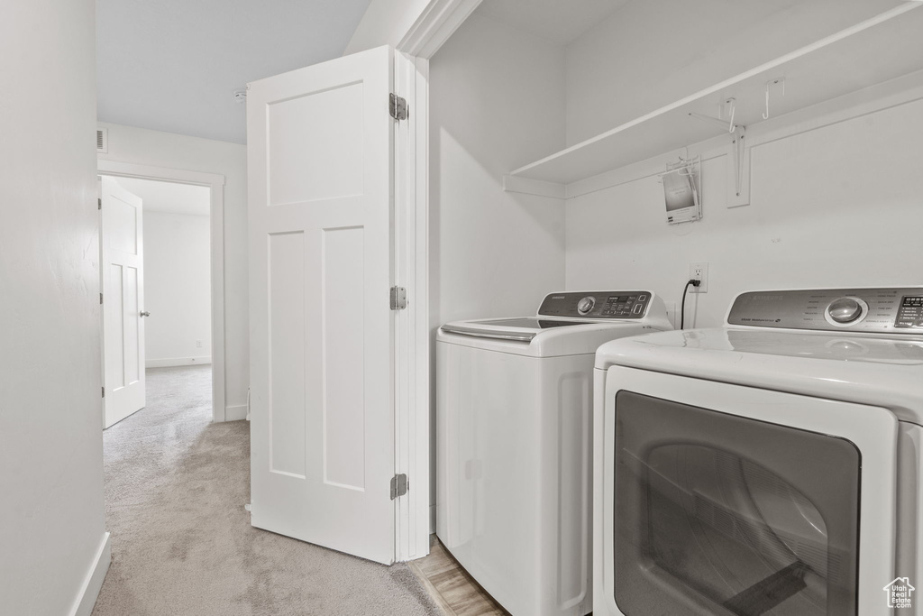 Laundry room with washing machine and dryer and light carpet