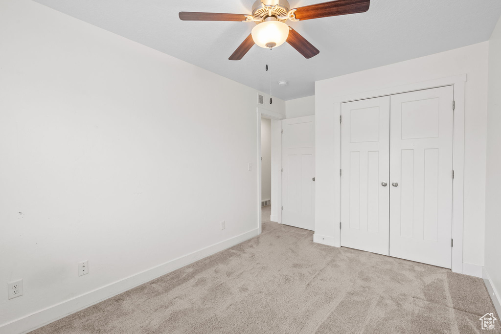 Unfurnished bedroom featuring carpet floors, a closet, and a ceiling fan