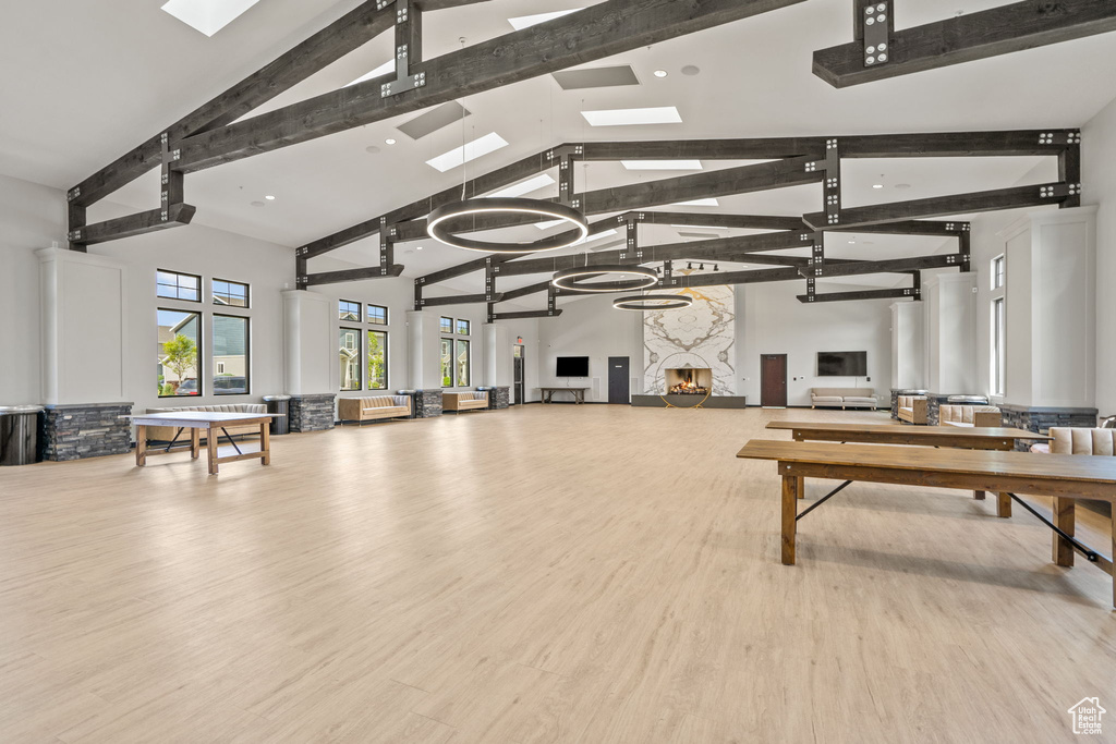 Misc room with beam ceiling, wood finished floors, high vaulted ceiling, and a skylight
