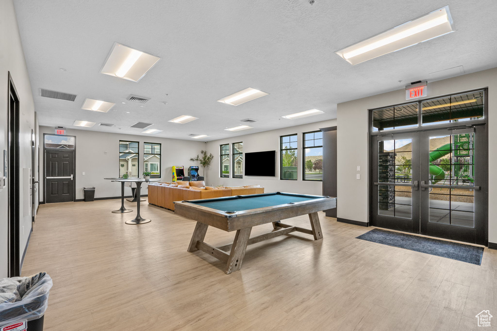 Recreation room with billiards table, light wood finished floors, and french doors