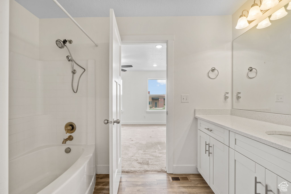 Bathroom with vanity, wood finished floors, and bathing tub / shower combination