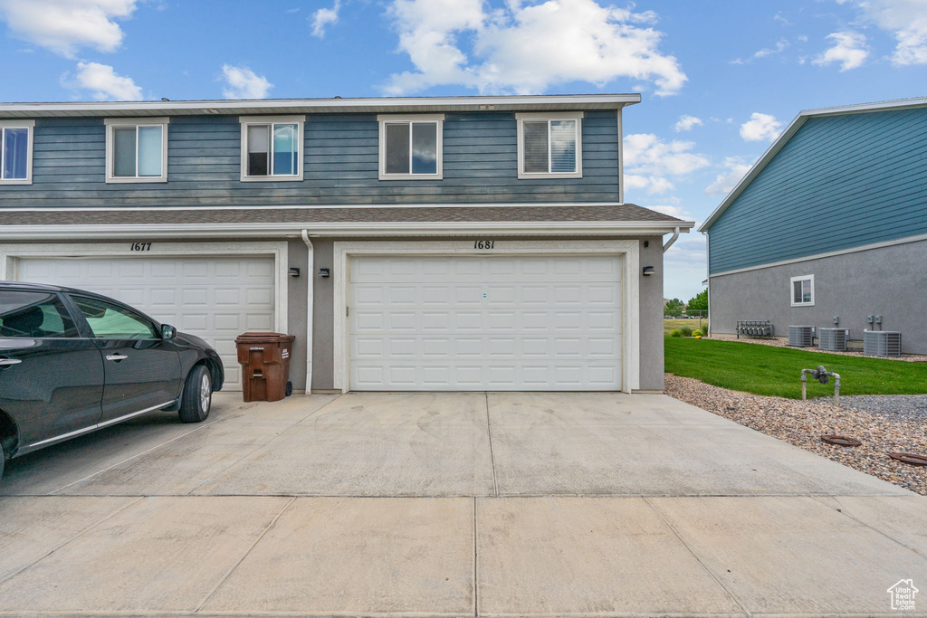 View of front of property with a front lawn, driveway, a garage, and stucco siding