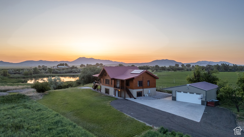 View of front of house with driveway, an outbuilding, a front lawn, a detached garage, and solar panels