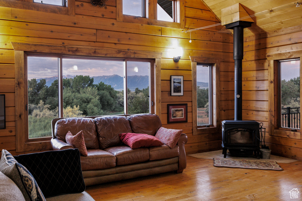 Living area with a wood stove, wood walls, plenty of natural light, hardwood / wood-style floors, and wood ceiling