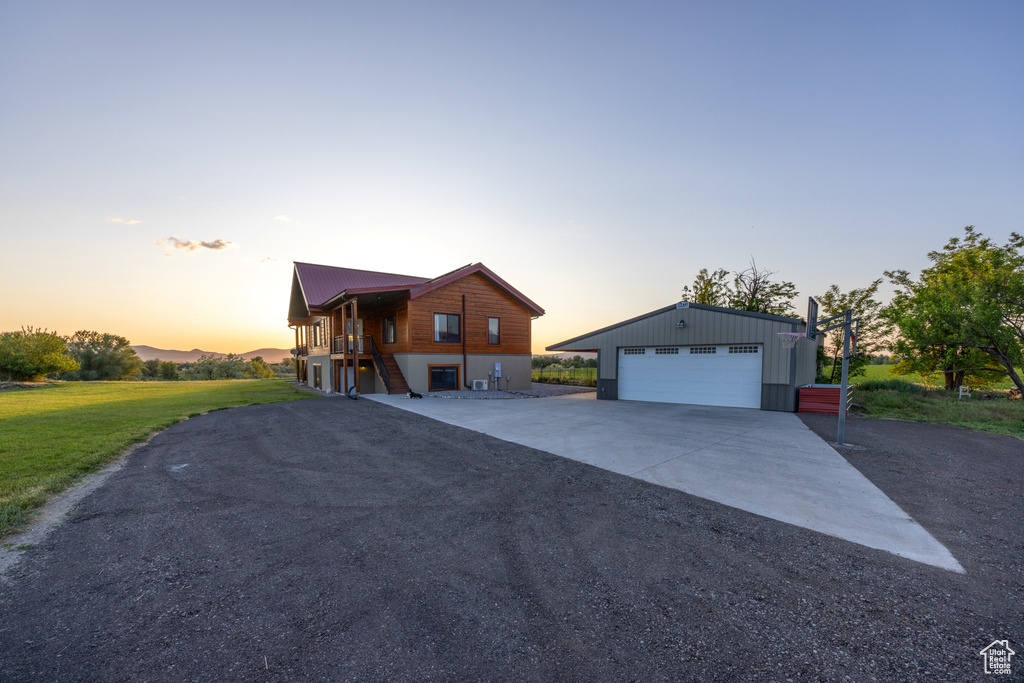 View of front of home featuring an outbuilding, a garage, a lawn, and stairway