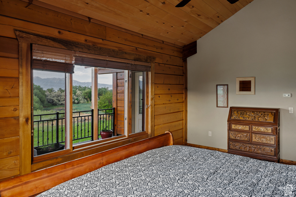 Bedroom featuring access to outside, vaulted ceiling, wooden ceiling, a mountain view, and wood walls