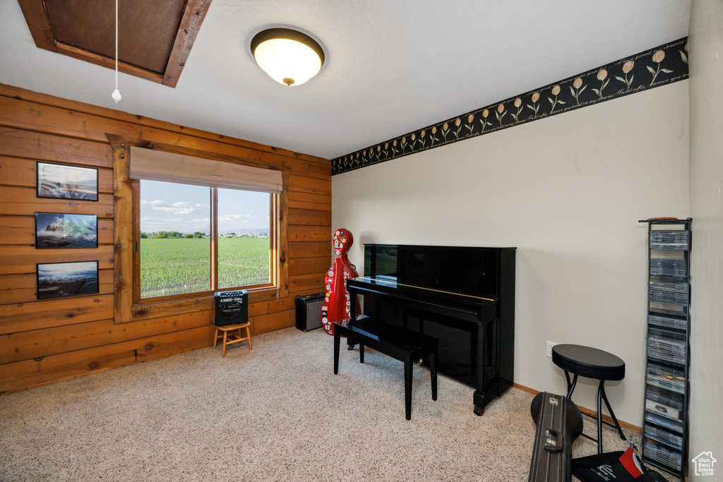 Living area featuring wooden walls, attic access, and carpet flooring