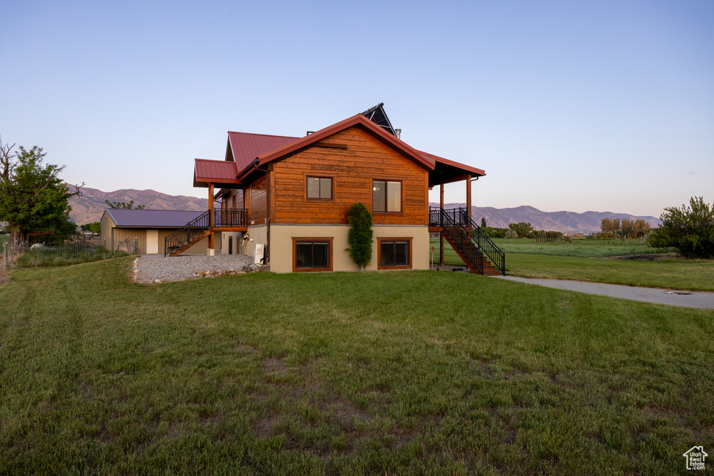 View of front of house with stairs, a lawn, a metal roof, and a deck with mountain view