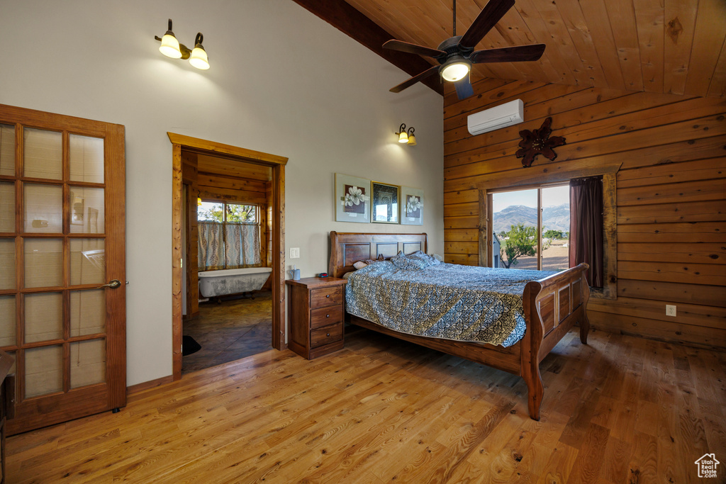 Bedroom featuring multiple windows, light wood finished floors, high vaulted ceiling, access to outside, and wood walls