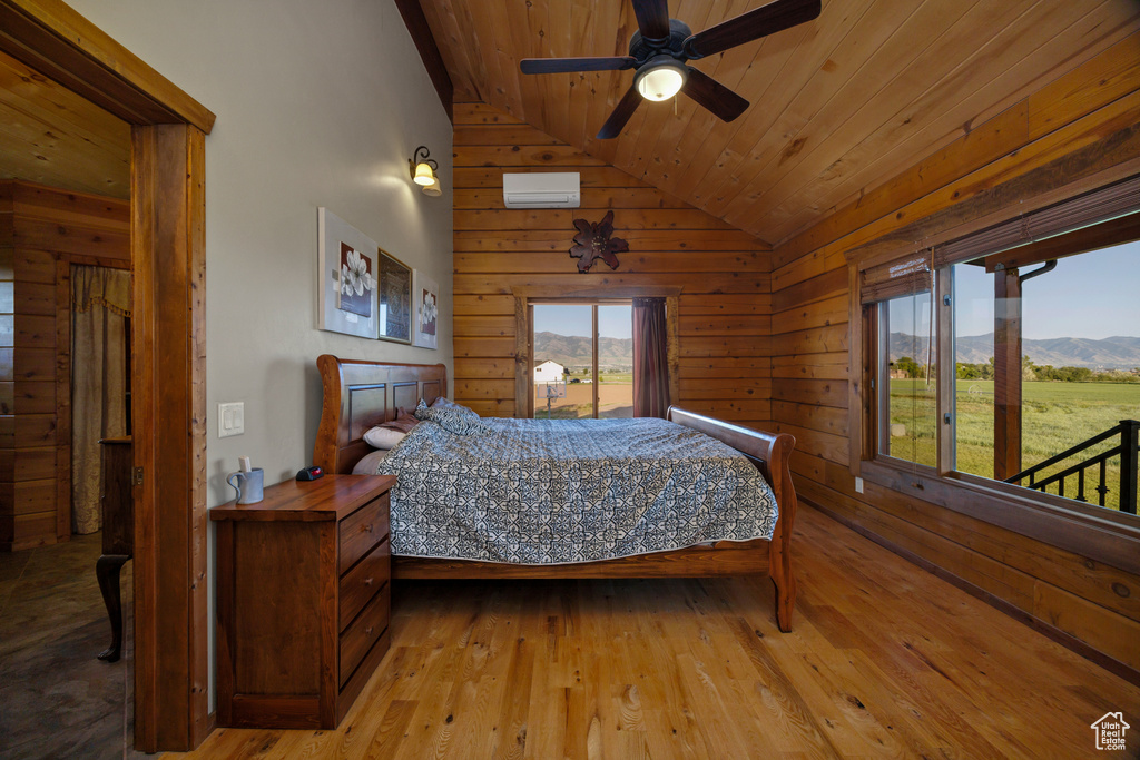 Bedroom featuring lofted ceiling, wood ceiling, wooden walls, a mountain view, and light wood-type flooring