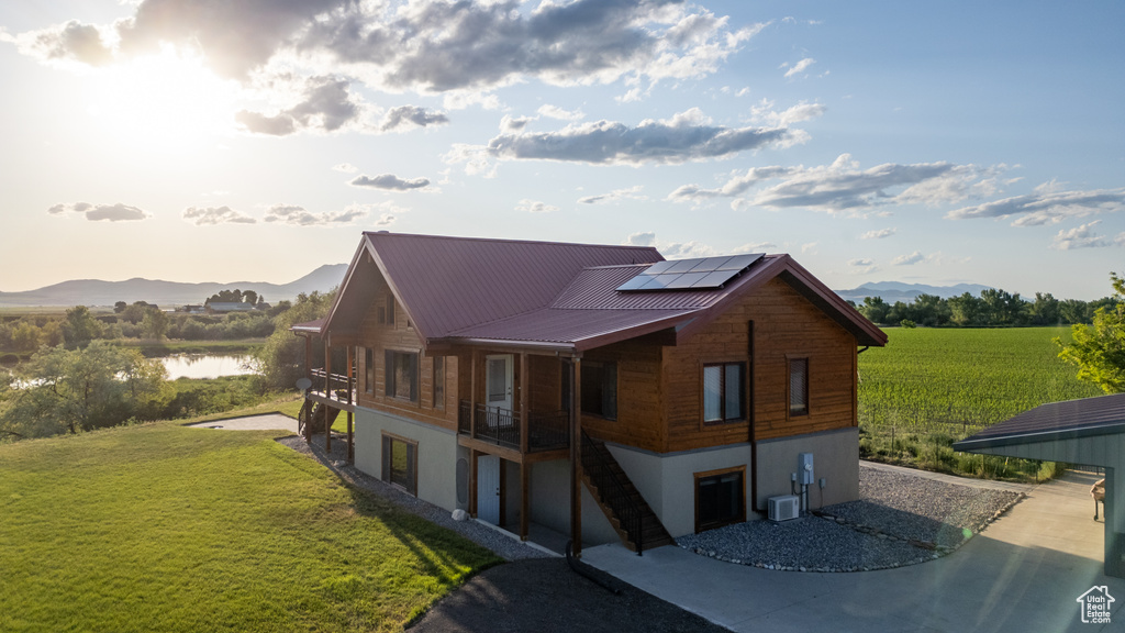 View of home\'s exterior with solar panels, a yard, a water and mountain view, and a metal roof