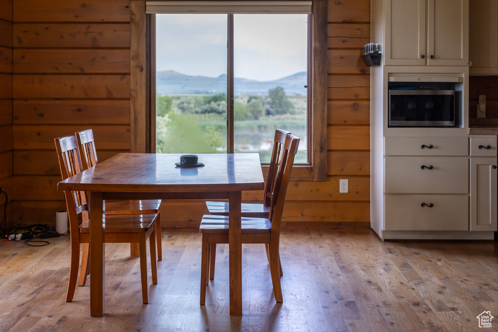 Dining space with light wood-type flooring, wood walls, and a mountain view
