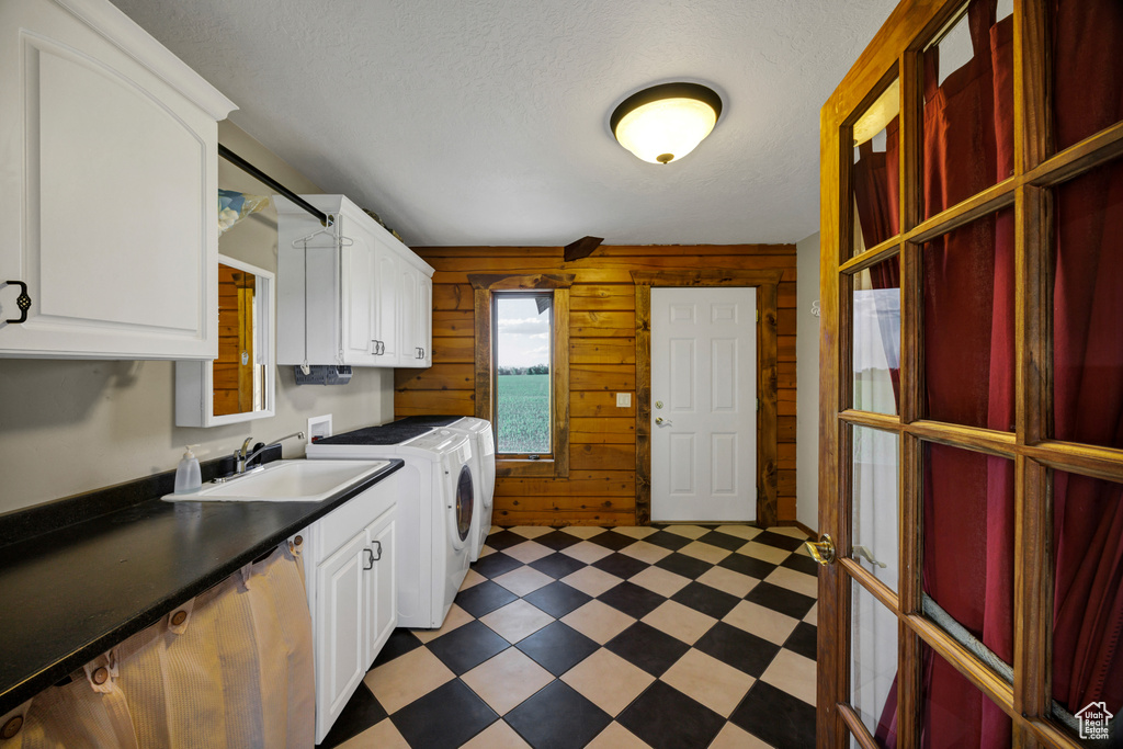 Laundry area featuring cabinet space, light floors, washer and clothes dryer, and wood walls