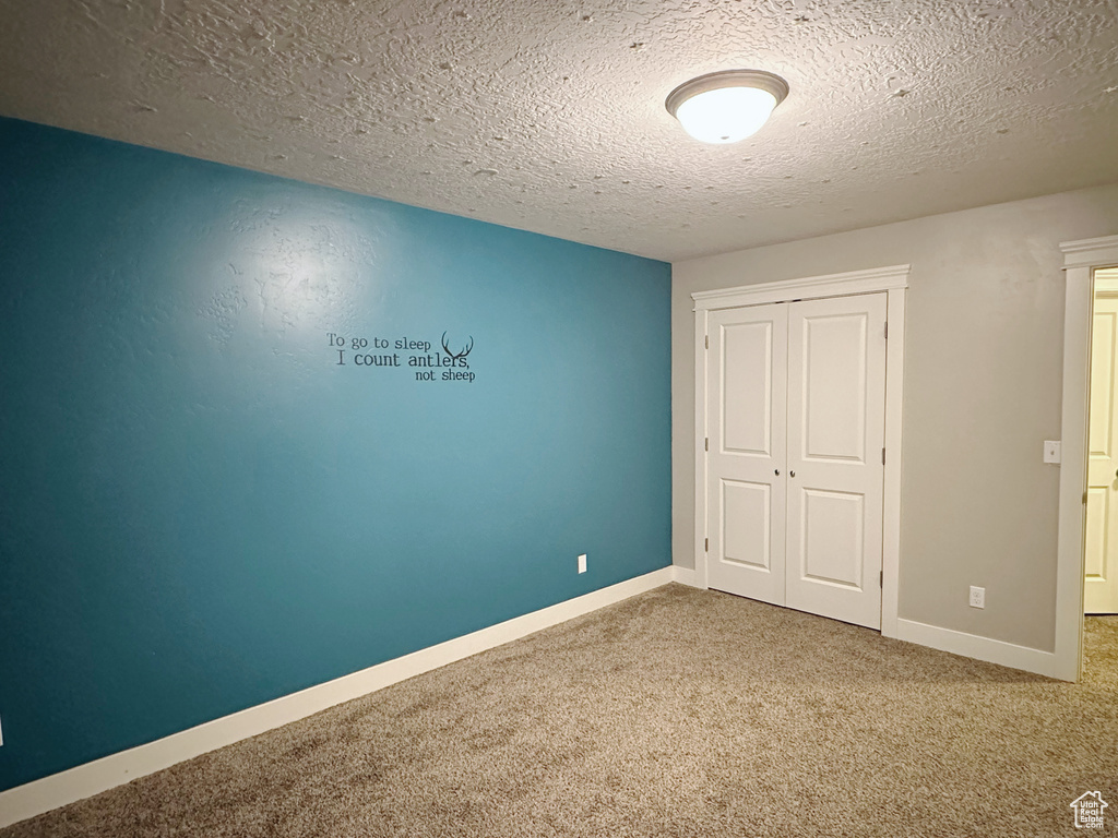 Unfurnished bedroom with a textured ceiling, carpet, and a closet