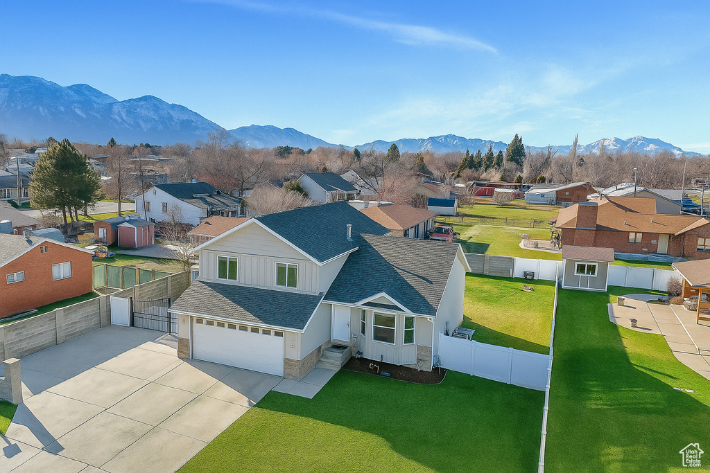 View of front of home featuring a residential view, a shingled roof, a garage, a fenced backyard, and stone siding