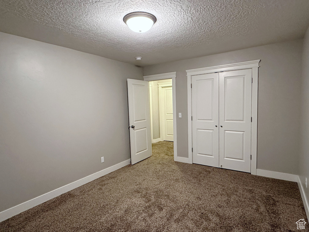 Unfurnished bedroom with carpet flooring, a textured ceiling, and a closet