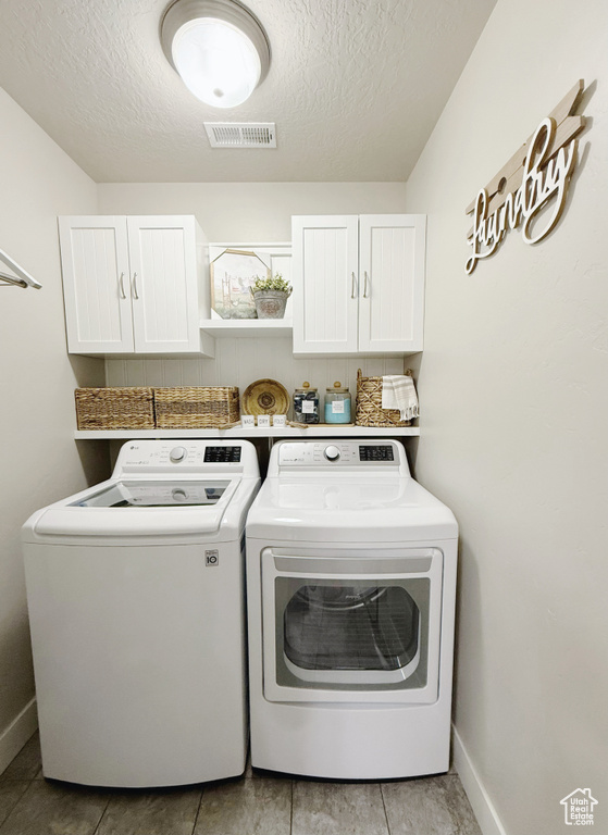 Laundry area with cabinet space, washer and dryer, and a textured ceiling