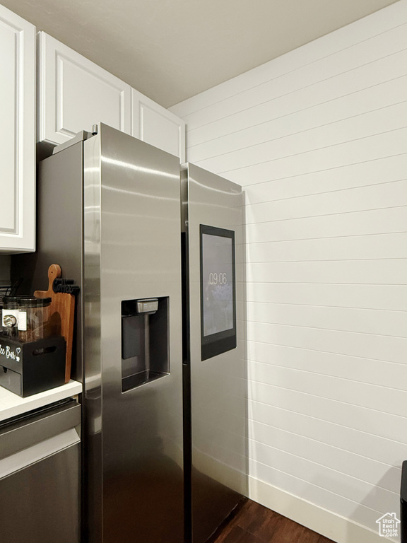 Kitchen featuring stainless steel refrigerator with ice dispenser, dark wood finished floors, and white cabinetry
