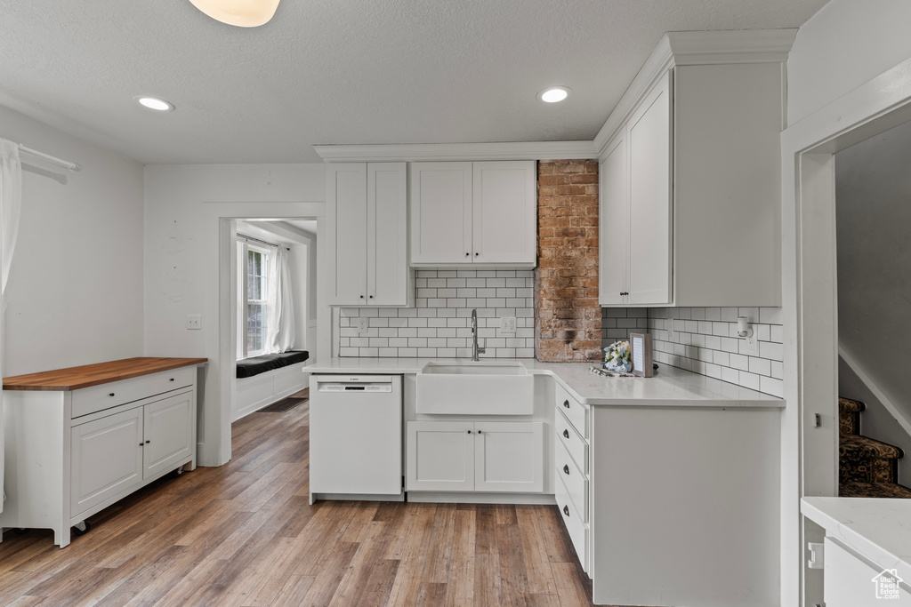 Kitchen featuring dishwasher, white cabinets, decorative backsplash, and recessed lighting