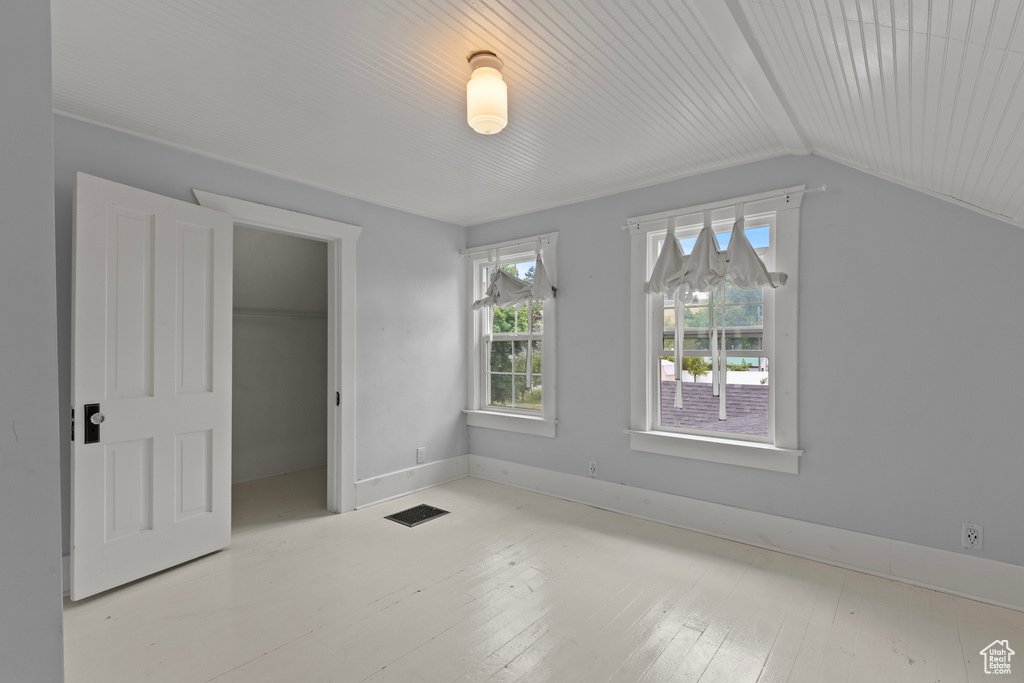 Unfurnished bedroom with vaulted ceiling, a walk in closet, and a closet