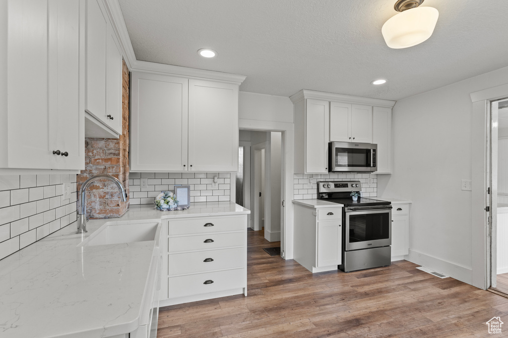 Kitchen featuring stainless steel appliances, tasteful backsplash, white cabinetry, and recessed lighting