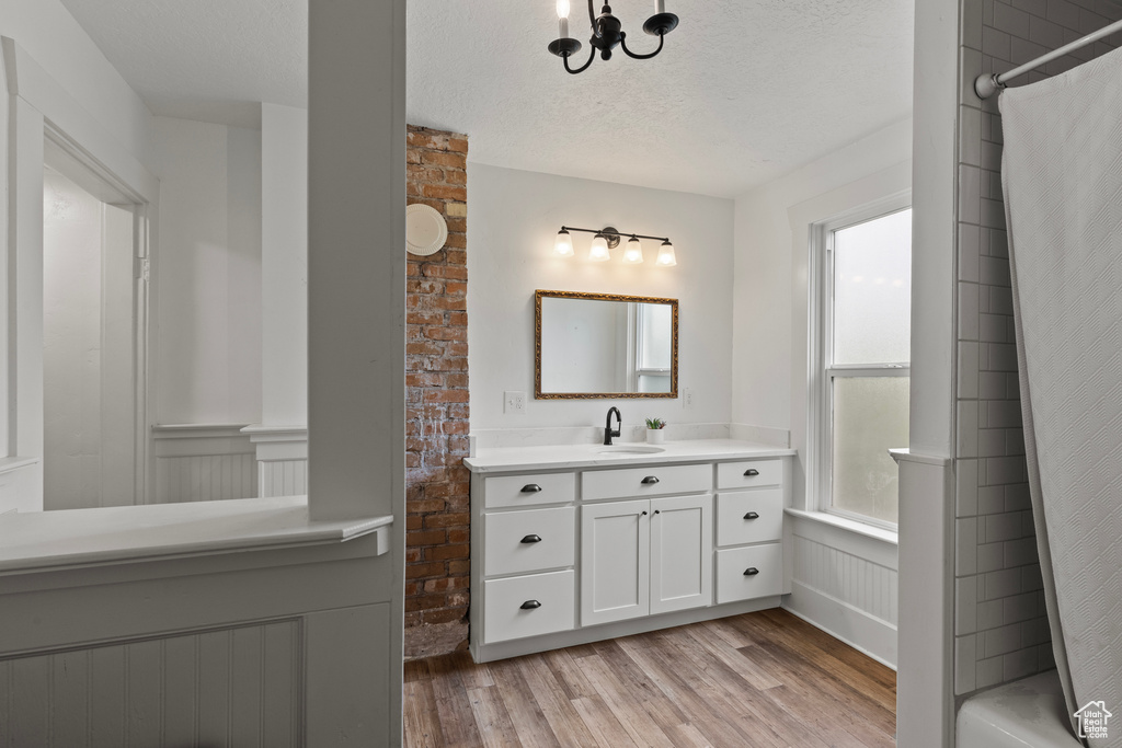 Bathroom featuring vanity, wood finished floors, a textured ceiling, a shower with curtain, and a chandelier