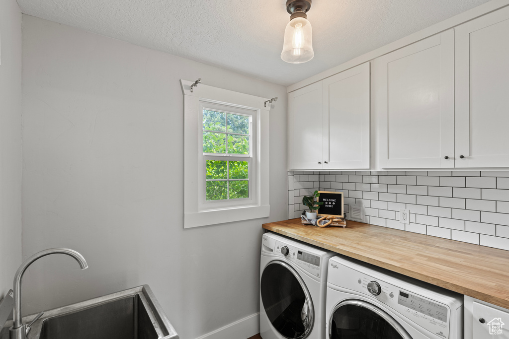 Laundry area with independent washer and dryer, cabinet space, and a textured ceiling