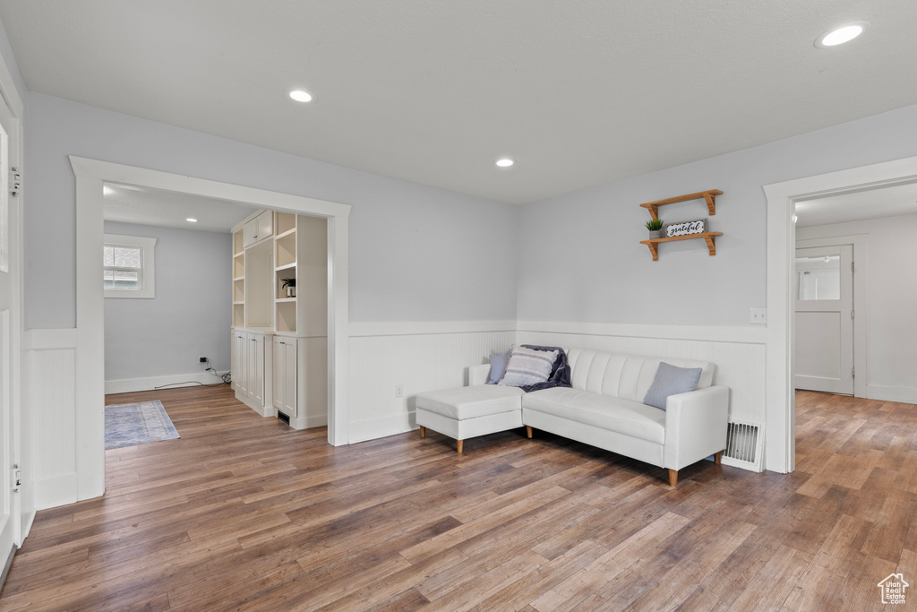 Living area featuring wainscoting, wood finished floors, recessed lighting, and a decorative wall