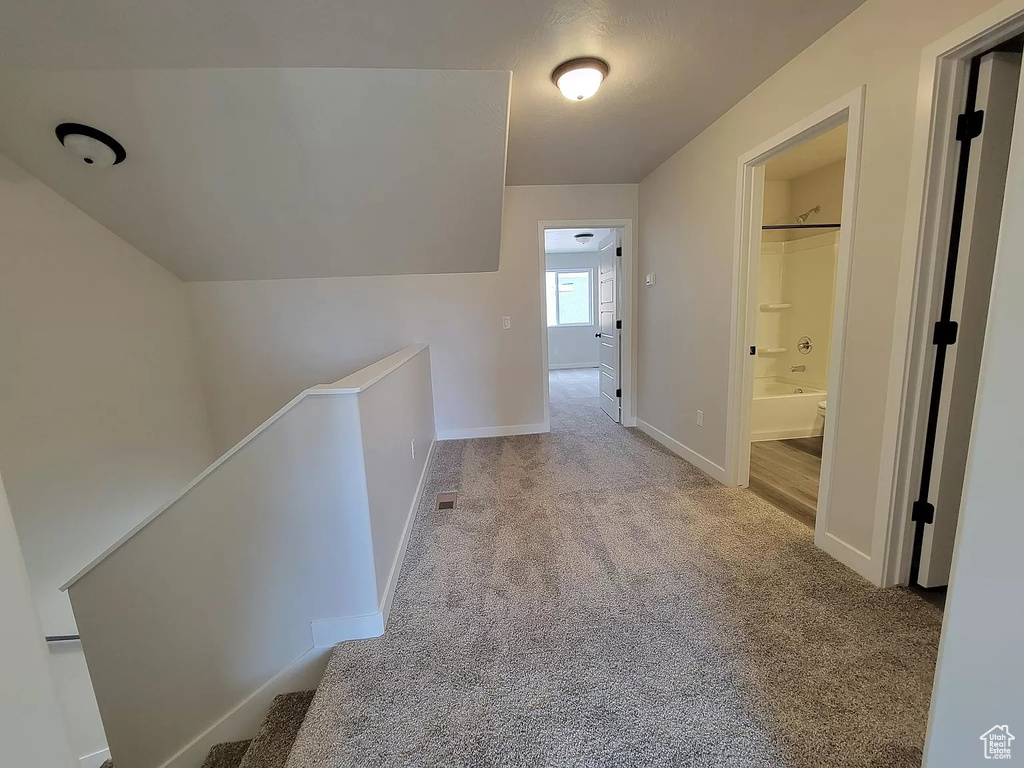 Corridor with carpet floors and an upstairs landing