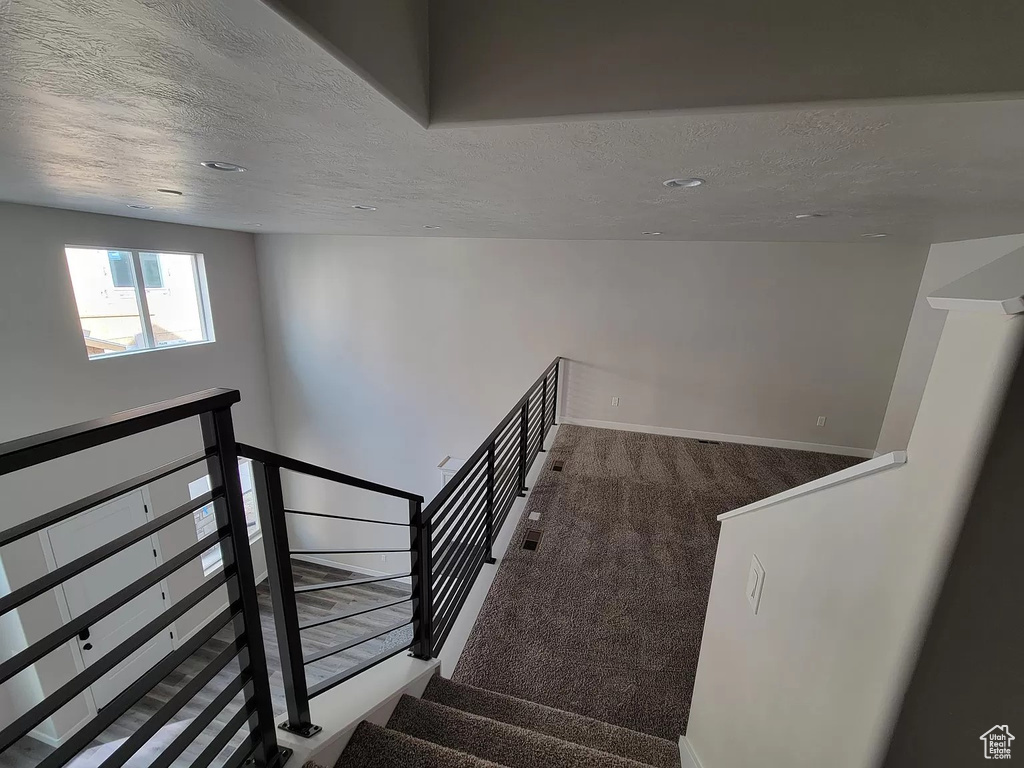 Stairs with a textured ceiling and carpet flooring