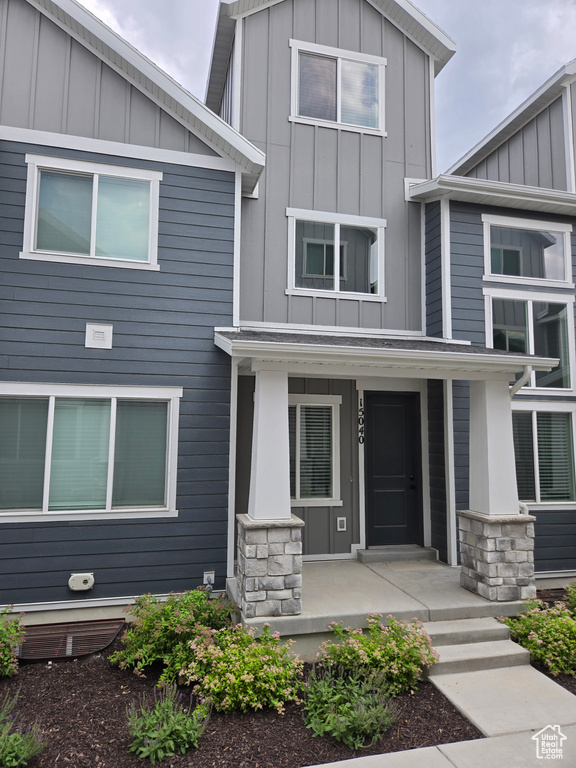 Contemporary home with board and batten siding, a porch, and stone siding