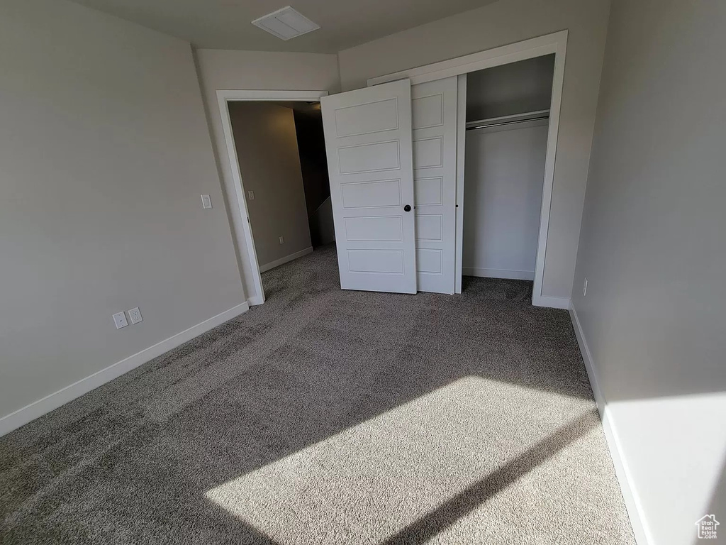 Unfurnished bedroom featuring carpet flooring and a closet