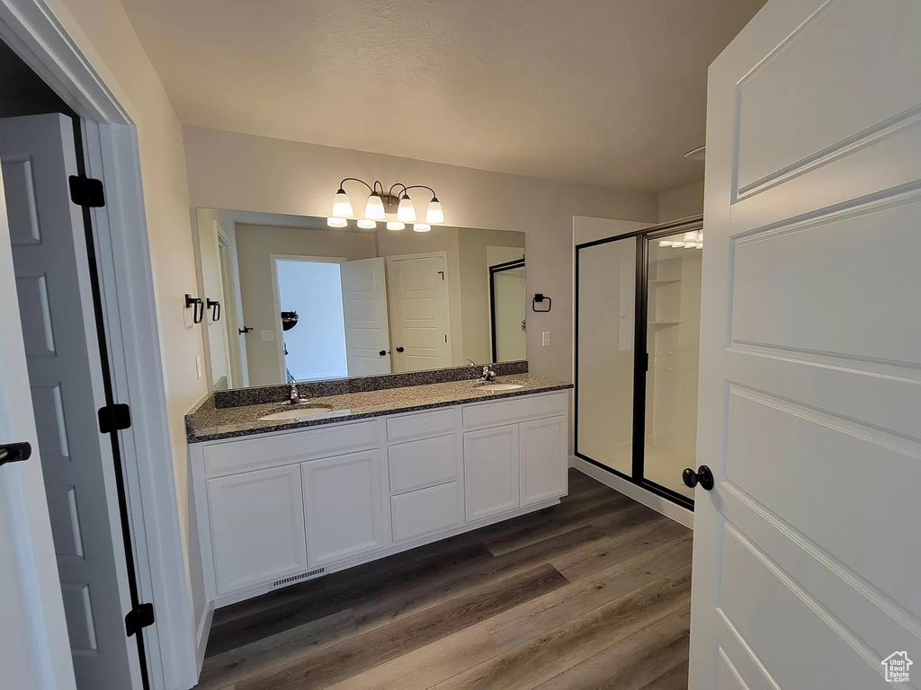 Full bath featuring wood finished floors, double vanity, a stall shower, and a chandelier