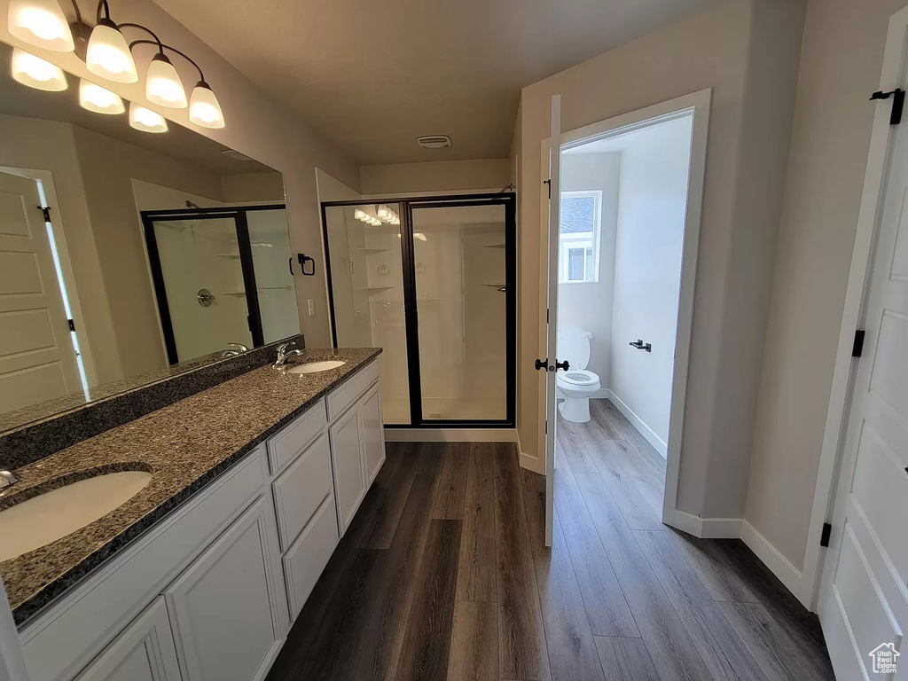 Bathroom with a shower stall, wood finished floors, and double vanity