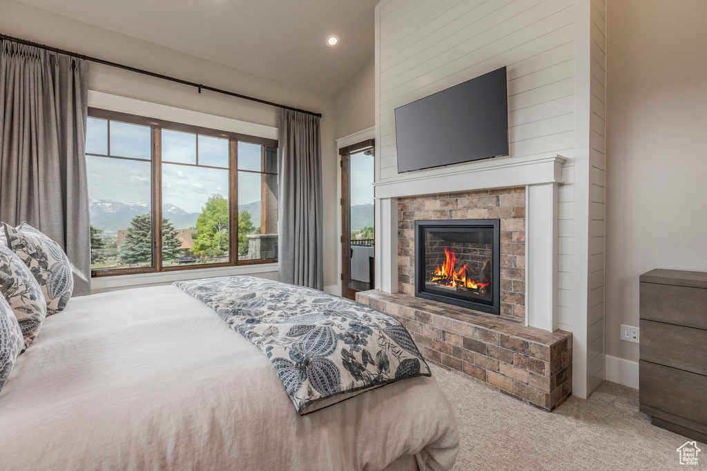 Bedroom featuring carpet flooring, vaulted ceiling, recessed lighting, and a glass covered fireplace