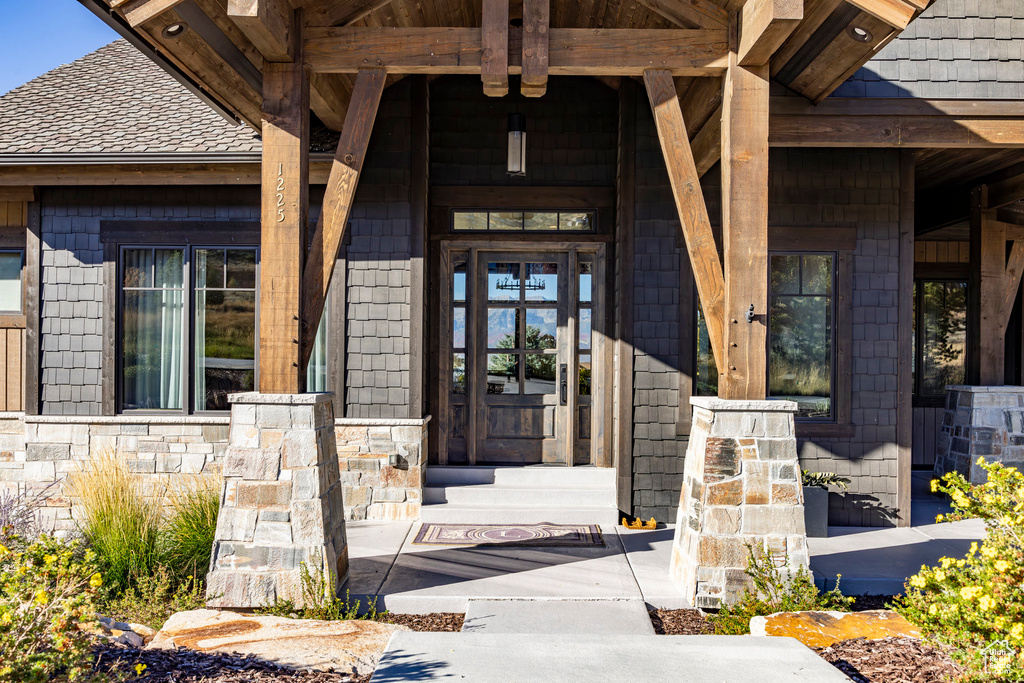 View of exterior entry featuring a porch and stone siding