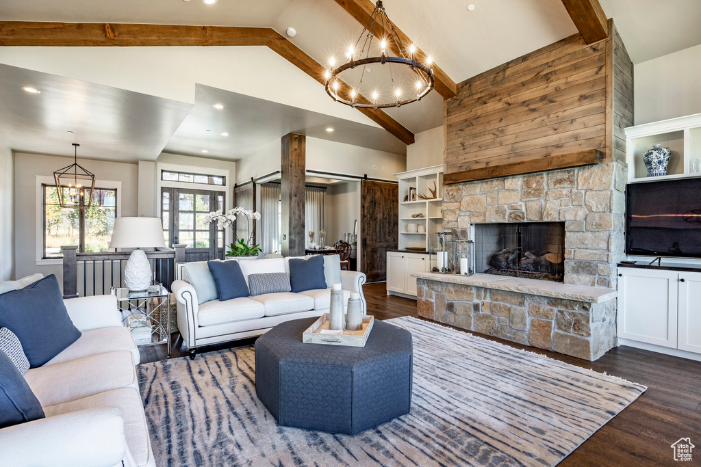 Living room with a chandelier, dark wood-style flooring, high vaulted ceiling, beam ceiling, and a stone fireplace
