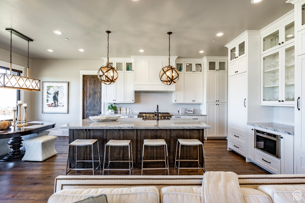 Kitchen with light stone countertops, a breakfast bar area, and recessed lighting