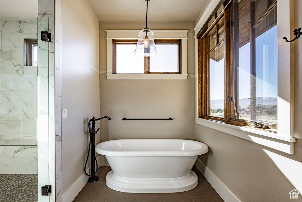 Bathroom featuring a marble finish shower, a freestanding bath, and tile patterned floors