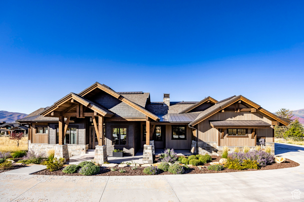 View of front of home with stone siding, a porch, a standing seam roof, a metal roof, and a mountain view