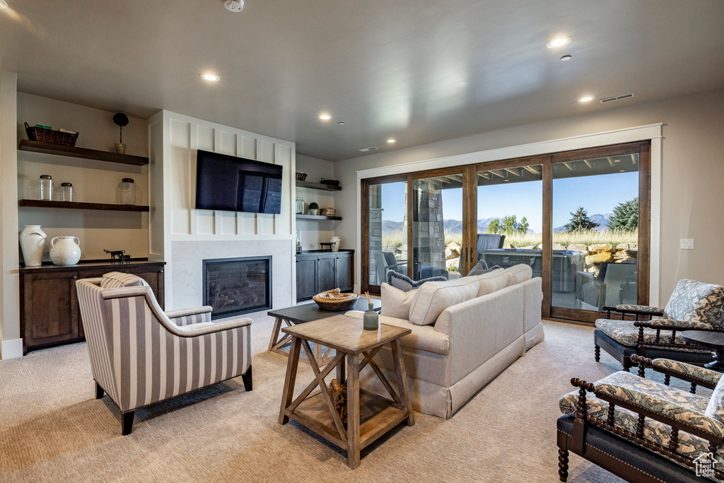 Living area with light colored carpet, a fireplace, and recessed lighting