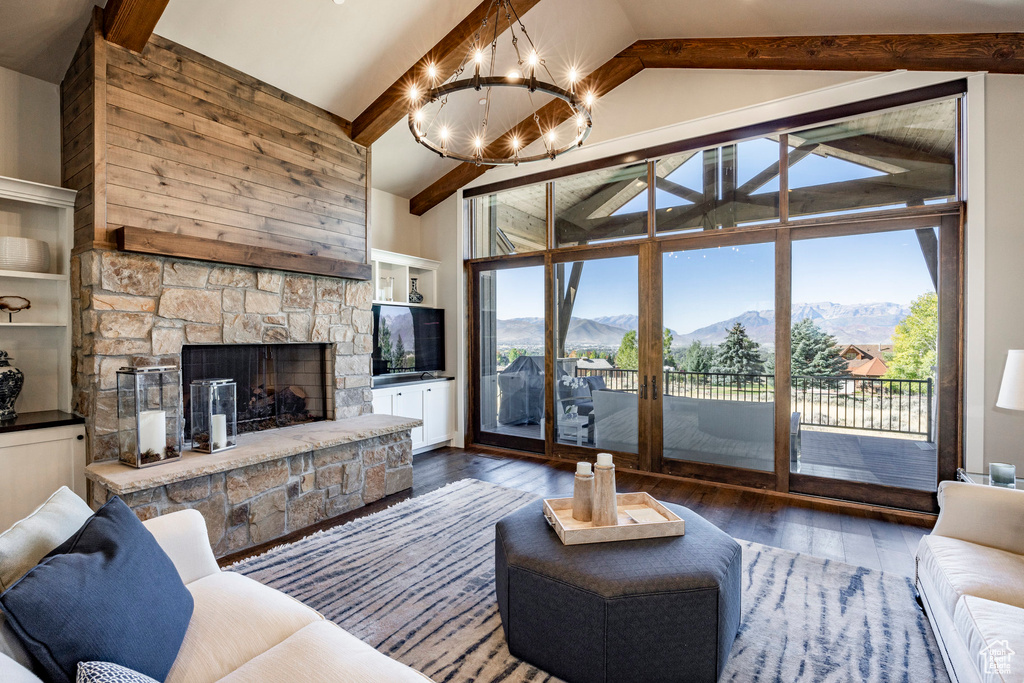 Living area with healthy amount of natural light, a chandelier, hardwood / wood-style flooring, beamed ceiling, and a fireplace