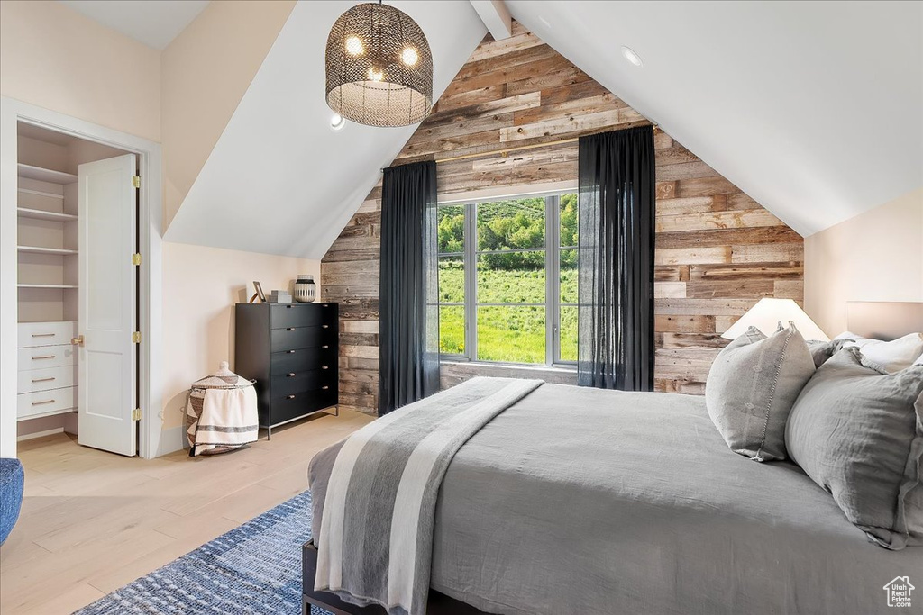 Bedroom with wood walls, wood finished floors, and a walk in closet