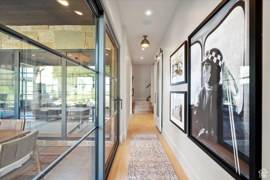 Hallway with plenty of natural light, light wood-style flooring, stairway, recessed lighting, and a barn door